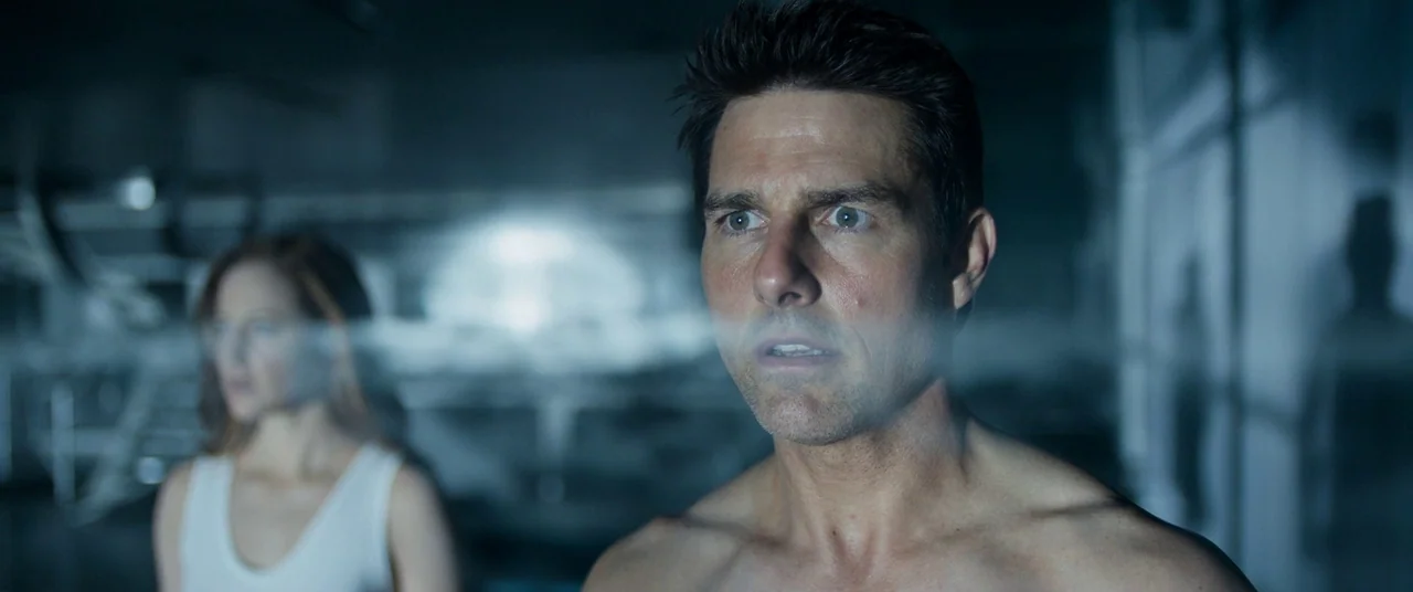 Oblivion (2013) movie still: medium — A dimly lit scientific facility features sterile surfaces and cool blue ambient light. A man and a woman look…