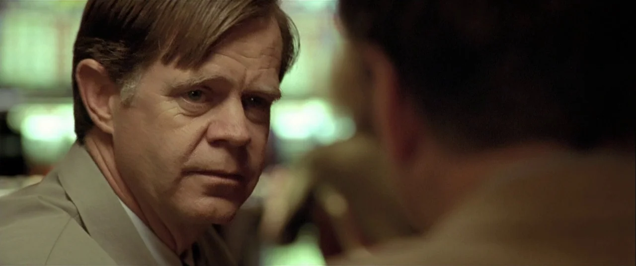 The Cooler (2003) movie still: closeup — A man in a tan blazer sits across from another person in a booth. The background is softly out of focus…