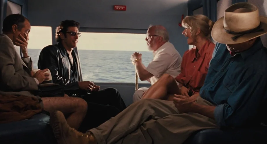 Jurassic Park (1993) movie still: wide — The interior of a helicopter flying over open water with blue-tinted panels. Five individuals are seated in…