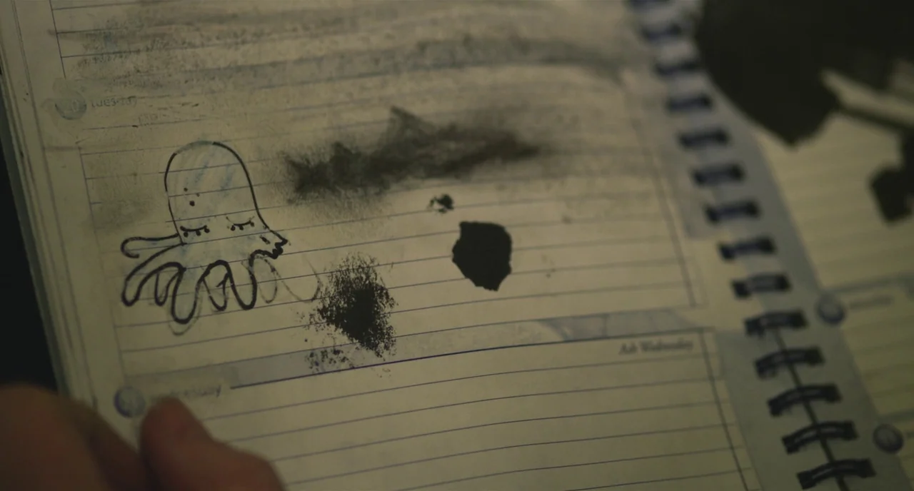 Short Term 12 (2013) movie still: closeup — A close-up of a spiral-bound planner page featuring a hand-drawn cartoon octopus. The page contains…