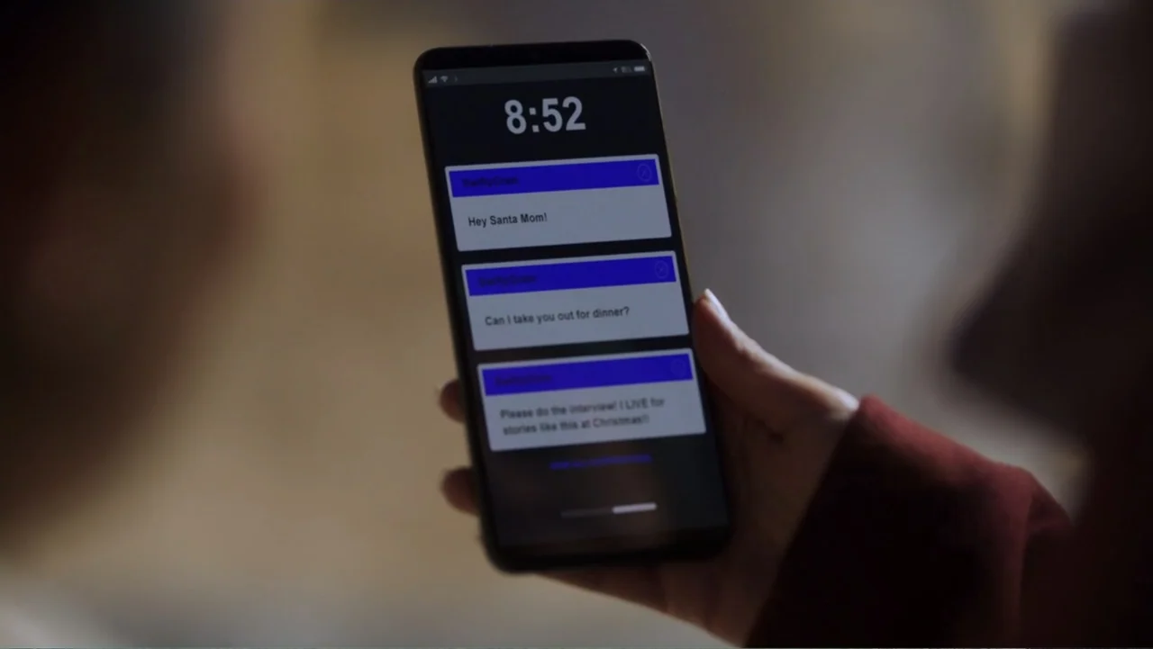 Peppermint and Postcards (2023) movie still: closeup — A person's hand holds a smartphone inside a dark indoor space. The screen displays three text…