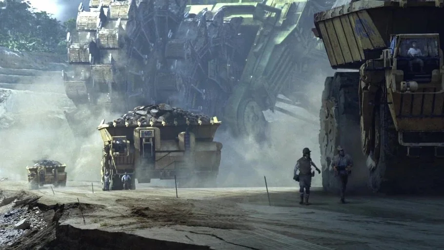 Avatar (2009) movie still: wide — A vast, dusty open-pit mining site features massive industrial vehicles navigating an earthen path. Workers walk…