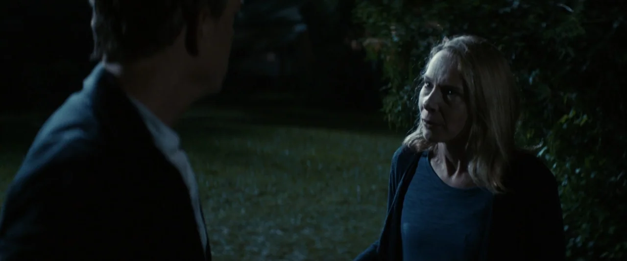 Strange but True (2019) movie still: medium — A dark outdoor area with dense foliage visible in the blurry background at night. A woman stands on a…