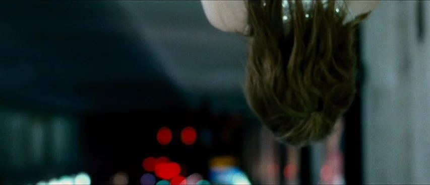 This Movie Is Broken (2010) movie still: closeup — A dark night street setting features out-of-focus city lights in the background. A person is…