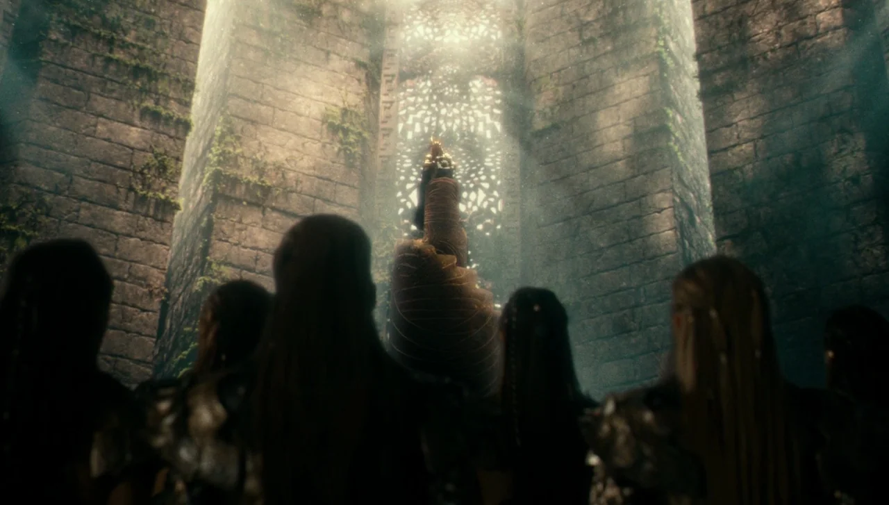 Justice League (2017) movie still: wide — A tall stone chamber features massive masonry pillars covered in moss and vertical ivy. A distant crowned…