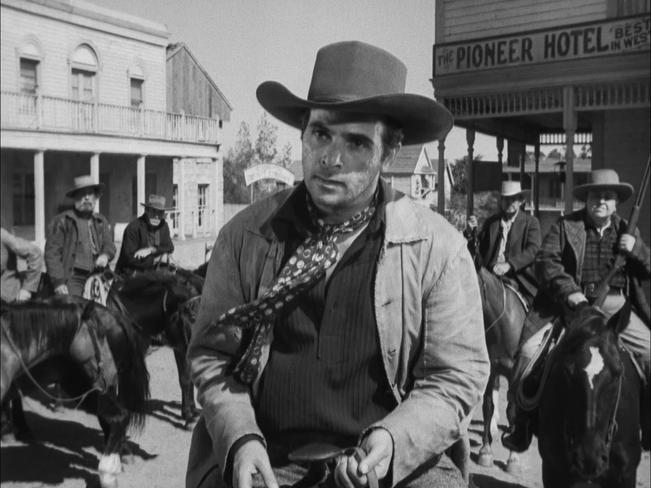 The Ox-Bow Incident (1942) movie still: medium — A group of men on horseback gathers in front of a wooden hotel building. The central rider wears a…