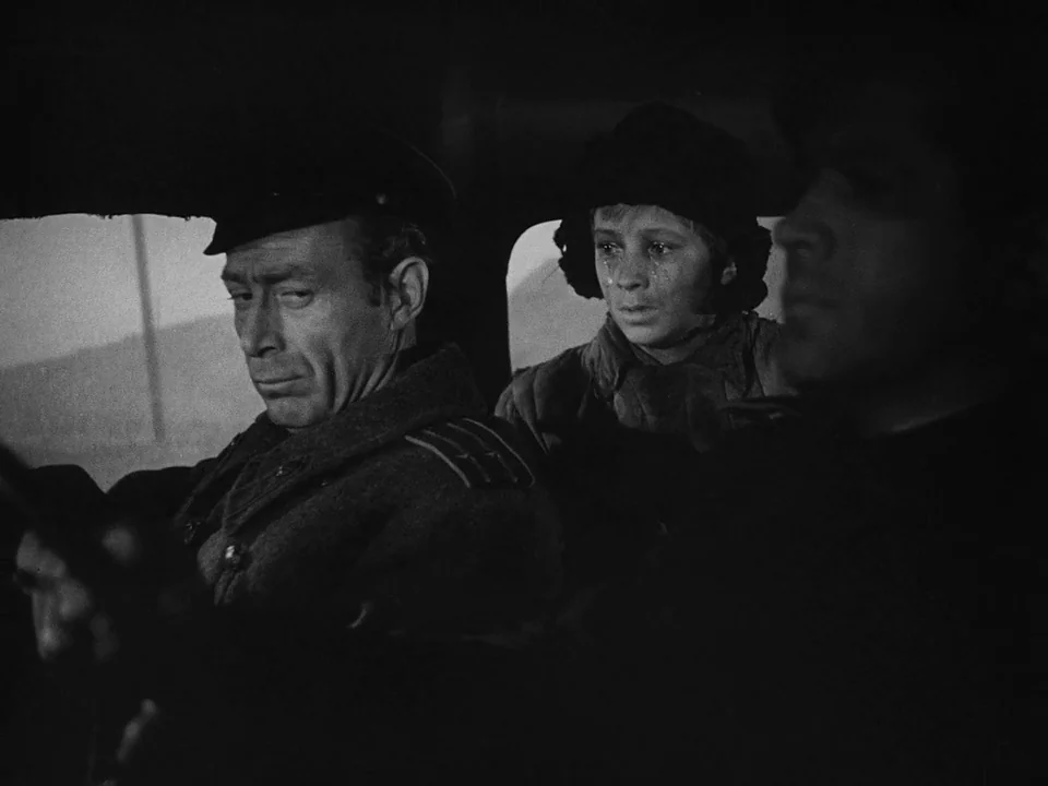 Ivan’s Childhood (1962) movie still: medium — The interior of a vintage vehicle shows a man driving and a child sitting behind. The child displays…