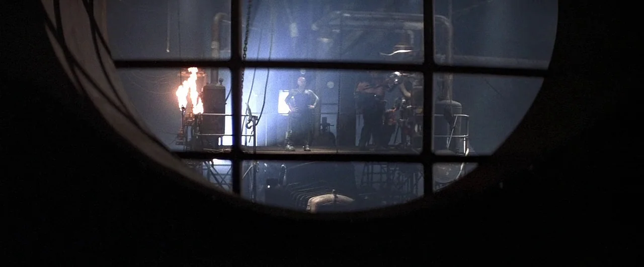 Mad Max Beyond Thunderdome (1985) movie still: wide — A dark industrial structure with exposed metal pipes viewed through a circular observation…