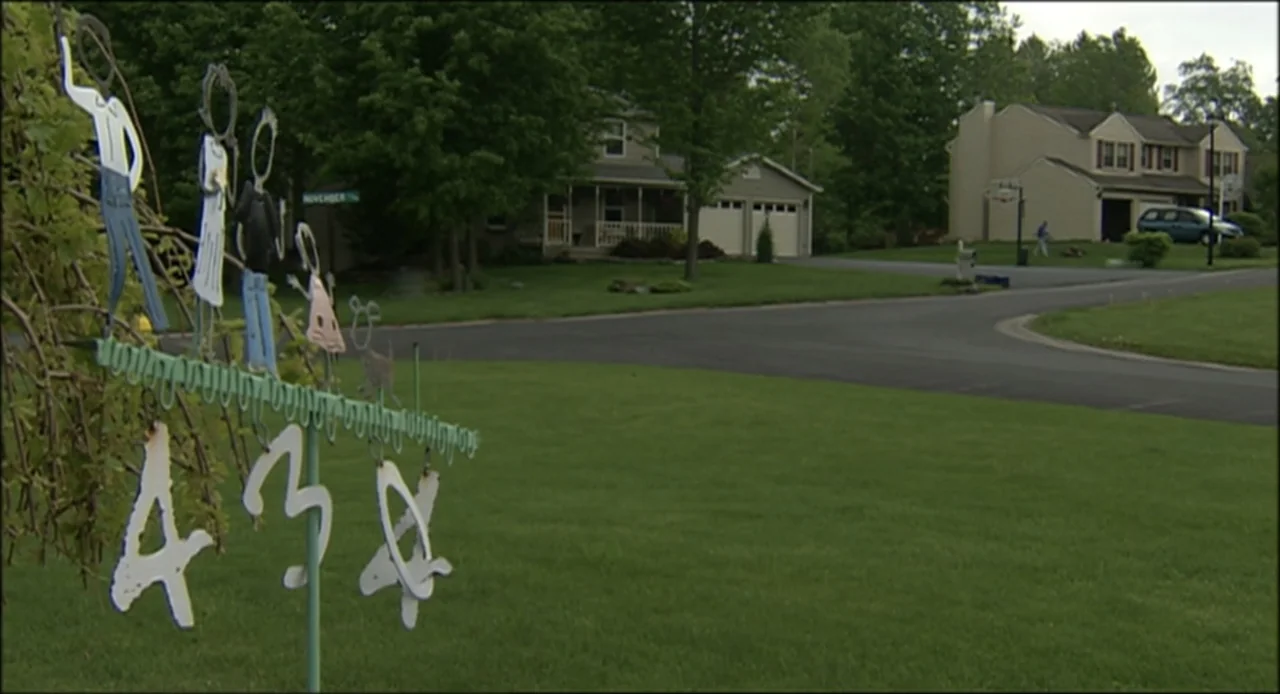Hard as Nails (2001) movie still: wide — A suburban cul-de-sac features manicured lawns and two-story residential homes in the background. A metal…