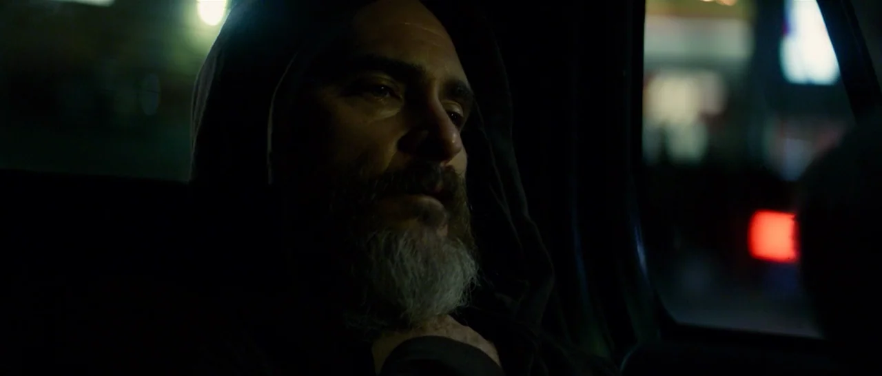 You Were Never Really Here (2017) movie still: closeup — A man sits in the back seat of a moving car at night. Outside the window, blurred city…