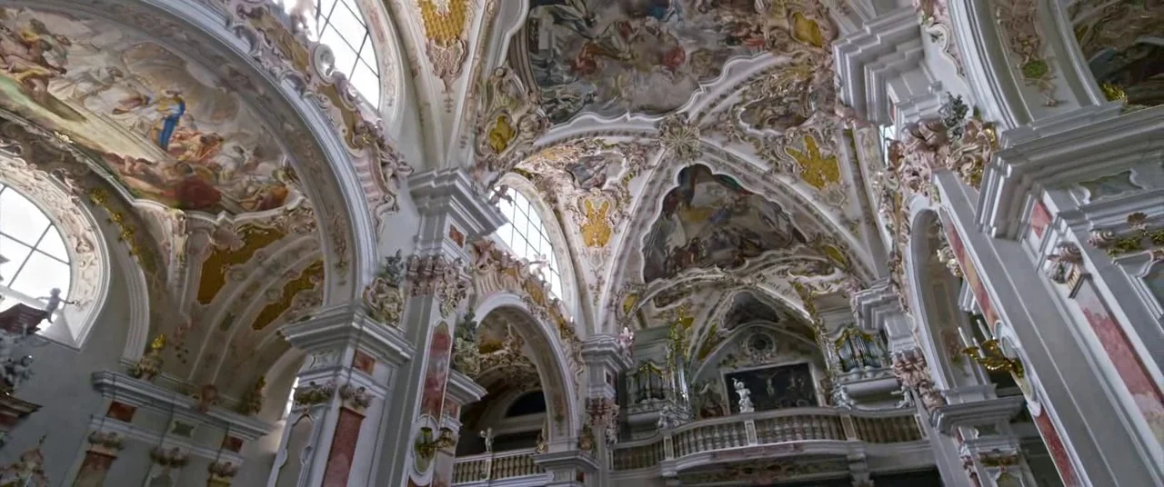 A Hidden Life (2019) movie still: establishing — A high-ceilinged cathedral interior features intricate Baroque architecture with elaborate frescoes…