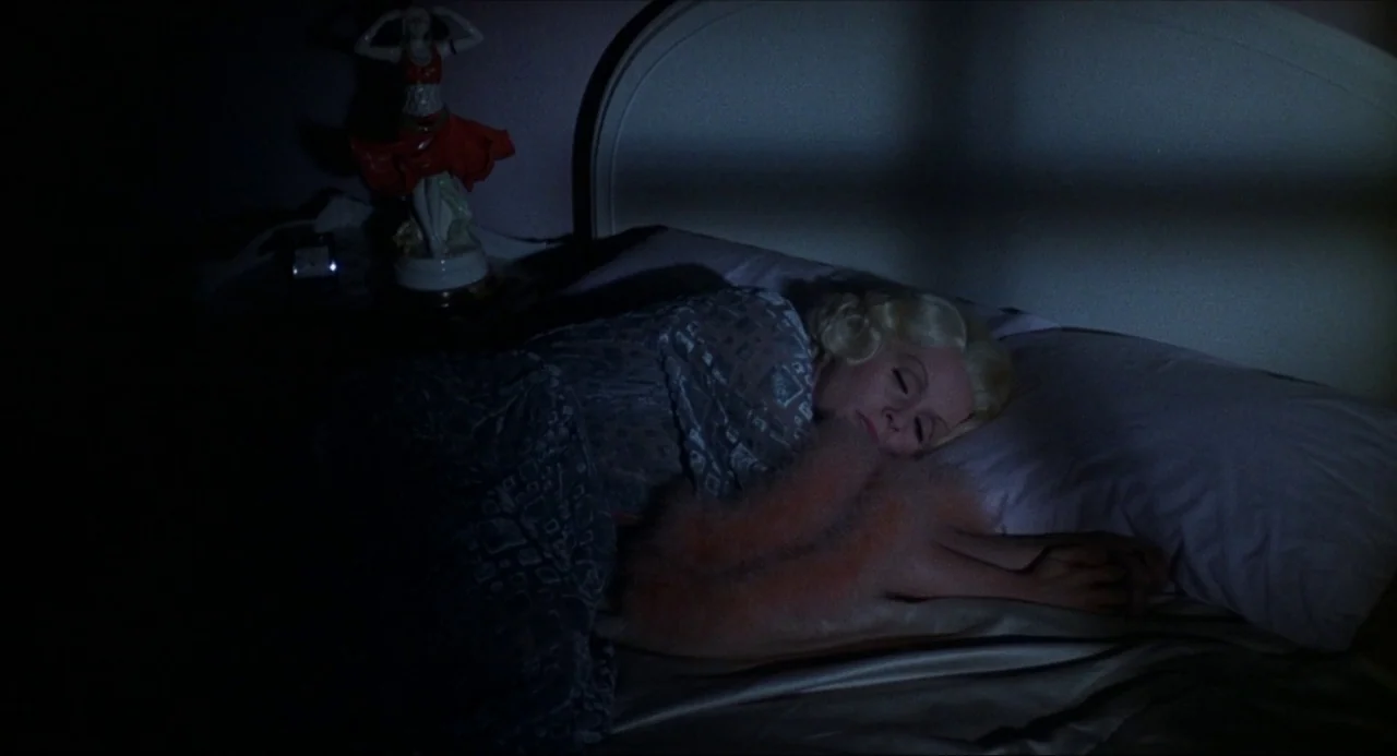 What’s the Matter with Helen? (1971) movie still: medium — A dark, dimly lit space features a woman sleeping in a bed. A porcelain figurine of a…