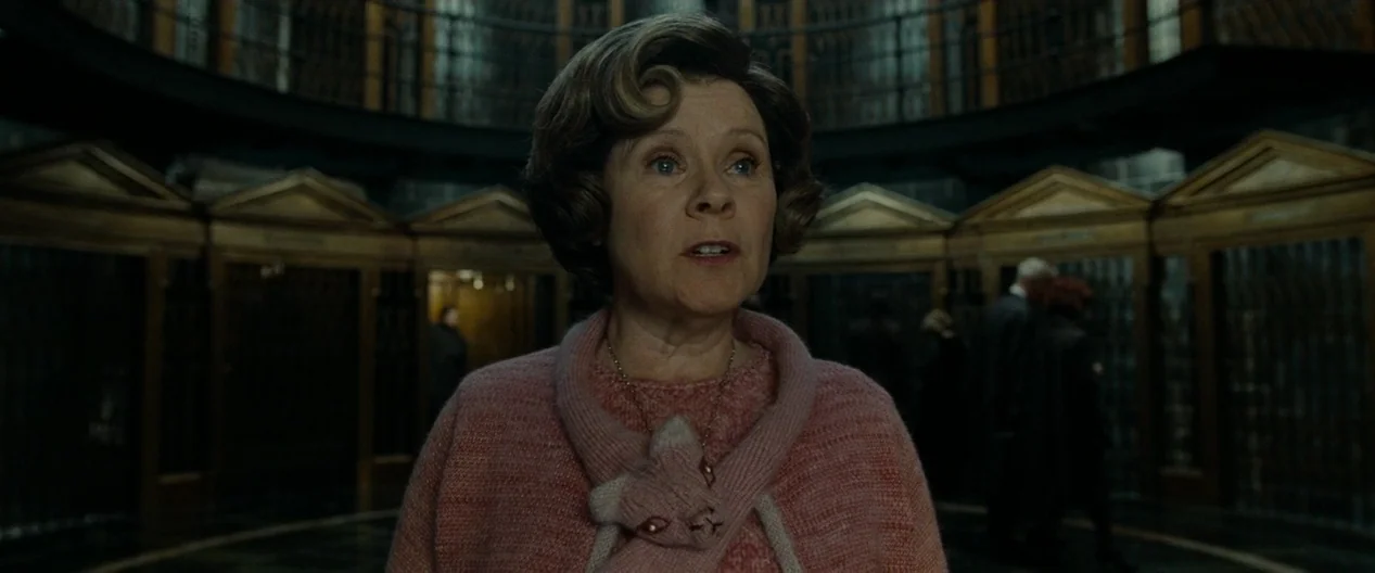 Harry Potter & The Deathly Hallows Part 1 (2010) movie still: medium — A dark, dimly lit institutional hall features multiple wooden partitions and…