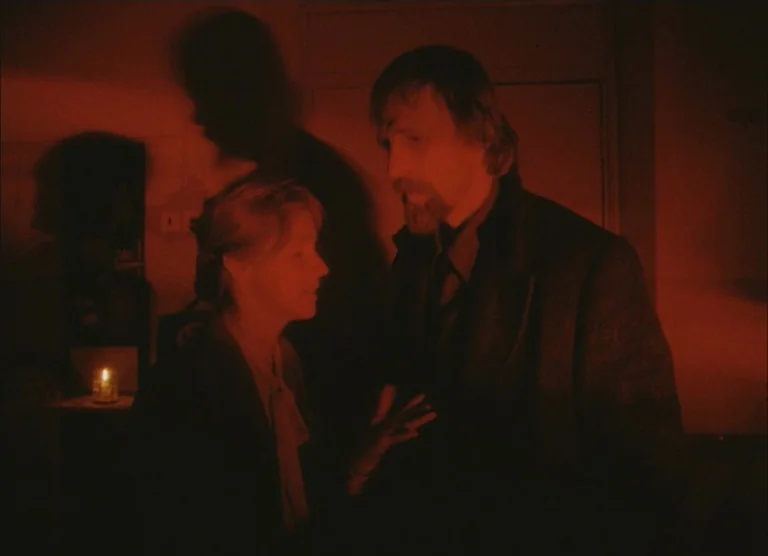 Russian Symphony (1994) movie still: medium — A dimly lit room is illuminated primarily by the flickering glow of a single candle. A man and a woman…