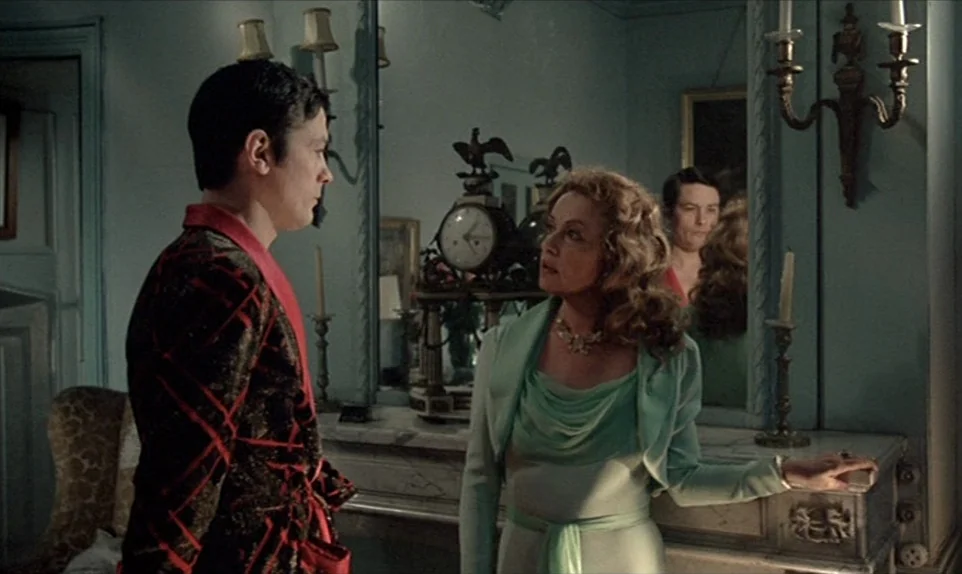 Mr. Klein (1976) movie still: medium — A lavish room with light blue walls features a large mantelpiece holding a clock. A man in a patterned gown…