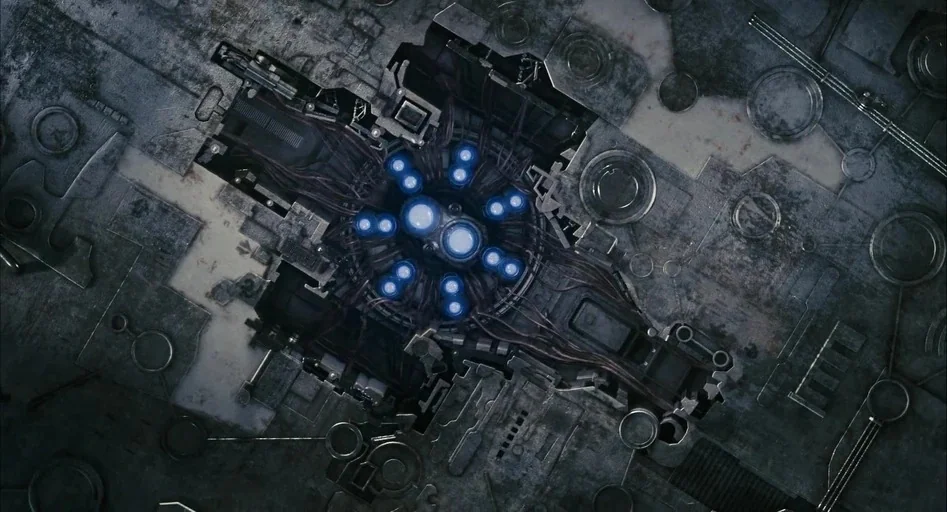 District 9 (2009) movie still: establishing — A complex piece of mechanical engineering is recessed into a cold metallic textured surface. Multiple…
