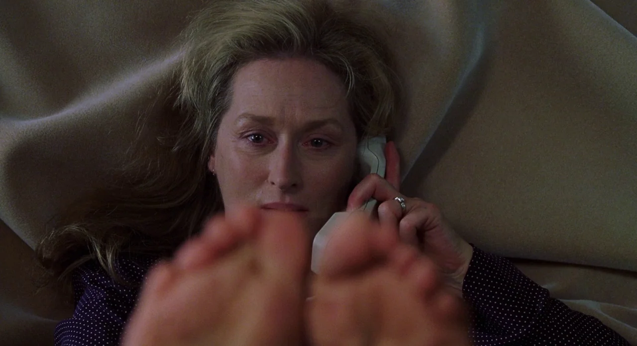 Adaptation (2002) movie still: closeup — A woman lies on a surface covered in soft beige fabric or bedding. She holds a telephone receiver to her…