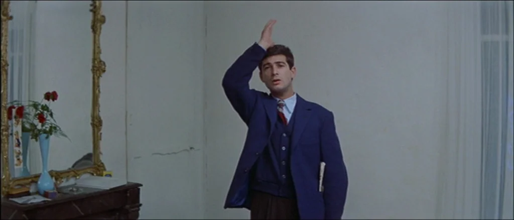Une Femme Est Une Femme (A Woman Is a Woman) (1961) movie still: medium — A sparsely furnished room features plain white walls and a large, ornate…