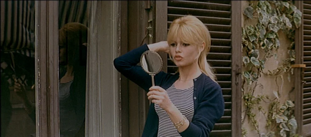 Contempt (Le Mépris) (1963) movie still: medium — An exterior area features dark wooden shutters and climbing ivy on a stone wall. A woman with…