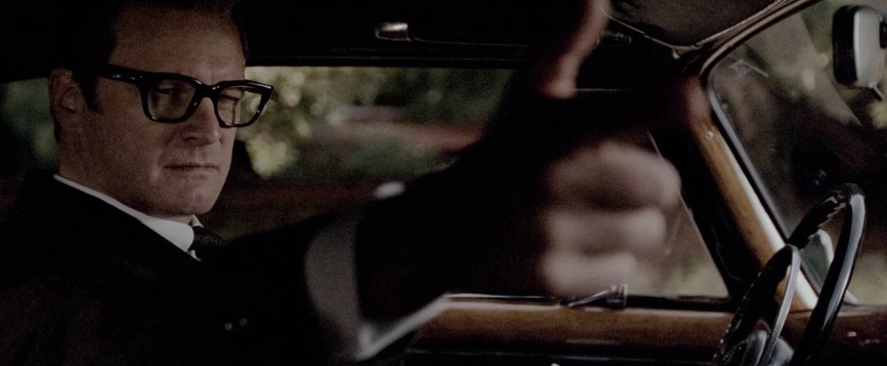 A Single Man (2009) movie still: medium — The interior of a vintage car features wooden dashboard trim and leather detailing. A man in a suit and…