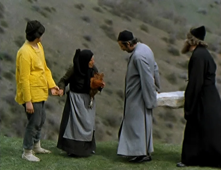 The Wishing Tree (1977) movie still: fullbody — A group of four people stand on a steep, sparse grassy hillside in daylight. They are holding…