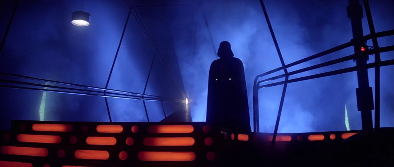 The Empire Strikes Back (1980) movie still: fullbody — A dark metal platform is shrouded in thick blue smoke with orange glowing accents. A cloaked…