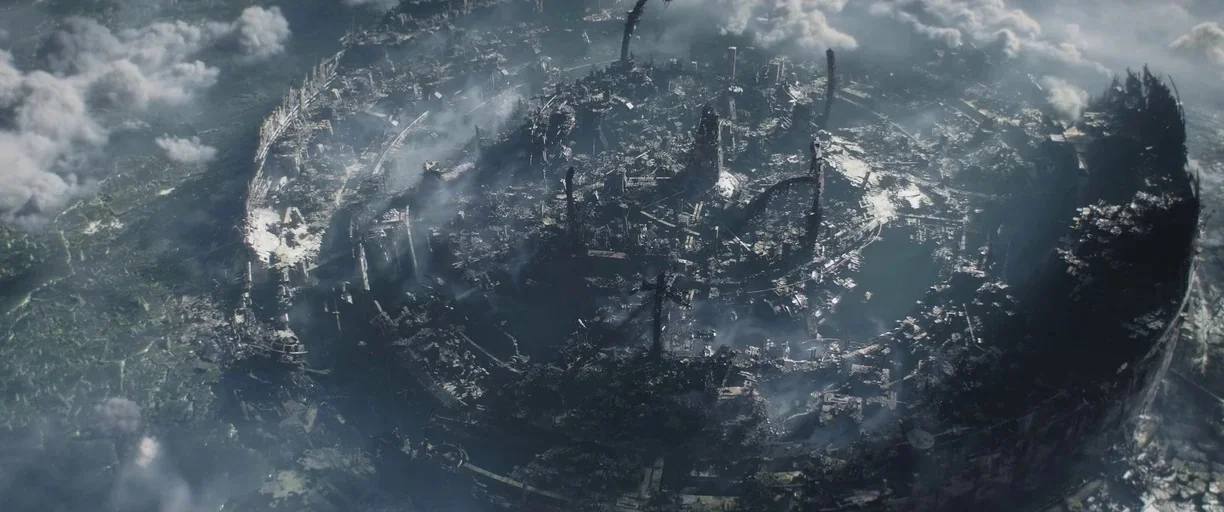 The Mandalorian (2019) movie still: establishing — A vast, circular city is reduced to rubble and twisted metal structures. Thick smoke drifts…