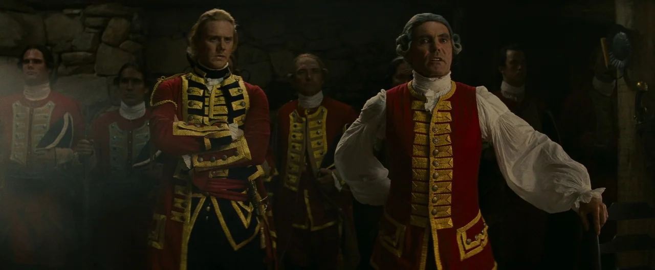 The Last of the Mohicans (1992) movie still: medium — A group of men in 18th-century military uniforms stand in a dark, stone-walled cellar. Two…