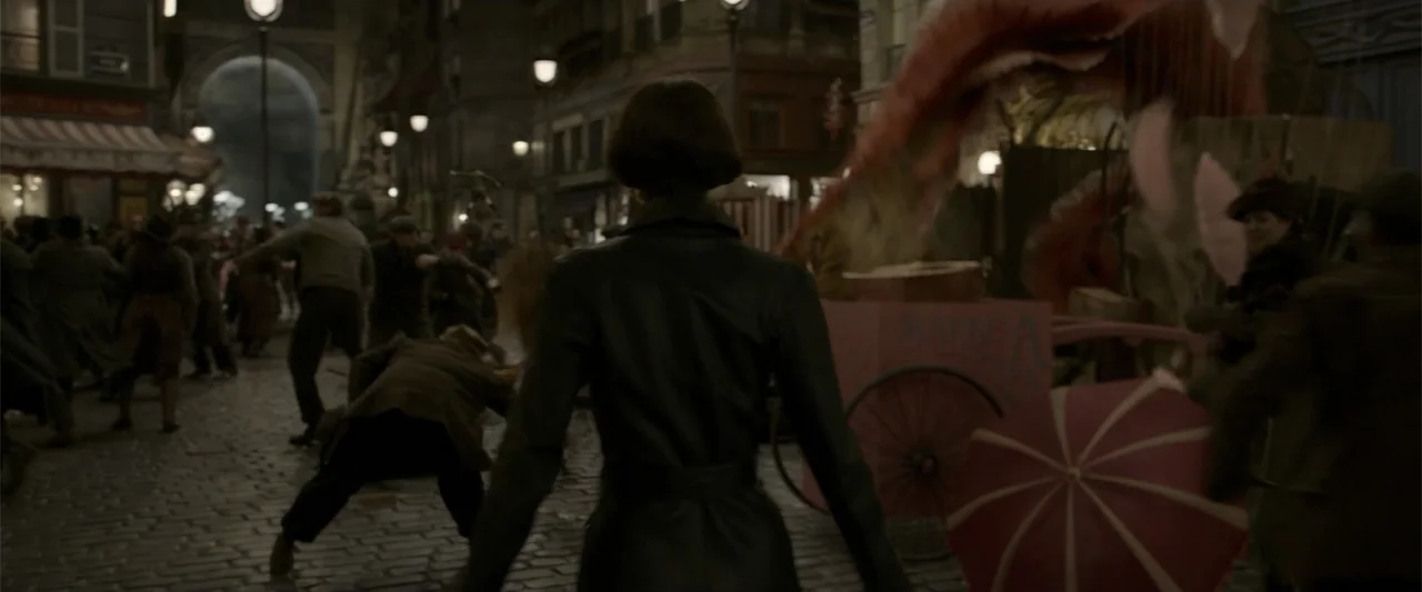 Fantastic Beasts: The Crimes of Grindelwald (2018) movie still: medium — A bustling 1900s cobblestone city street filled with moving people under…