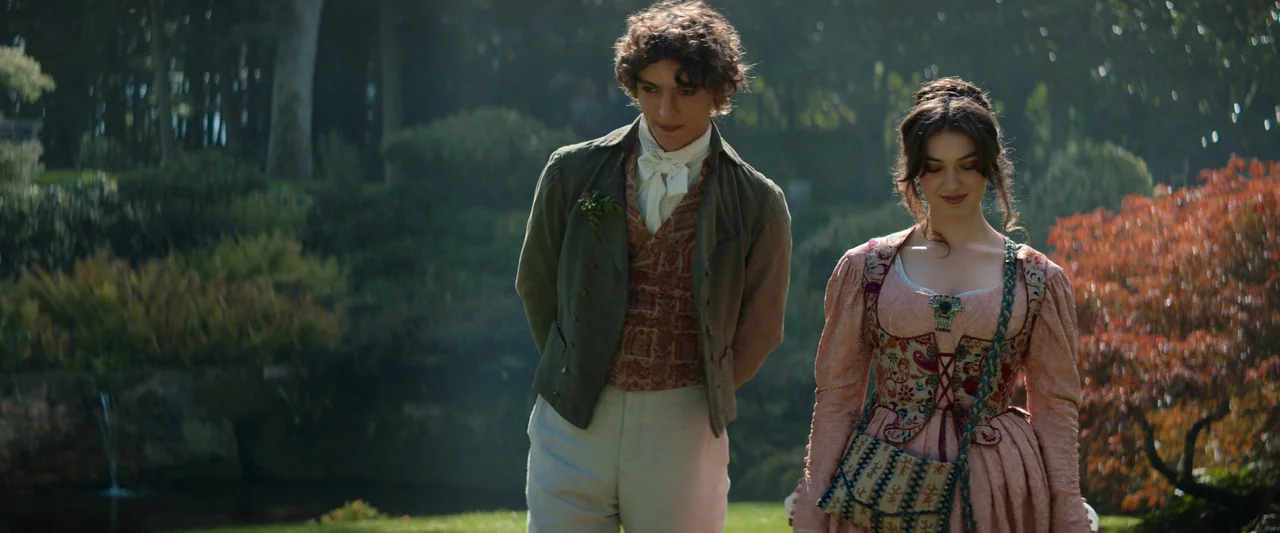 The Count of Monte-Cristo (2024) movie still: fullbody — A lush, green, sun-dappled landscape features trees and a small pond in the background. A…
