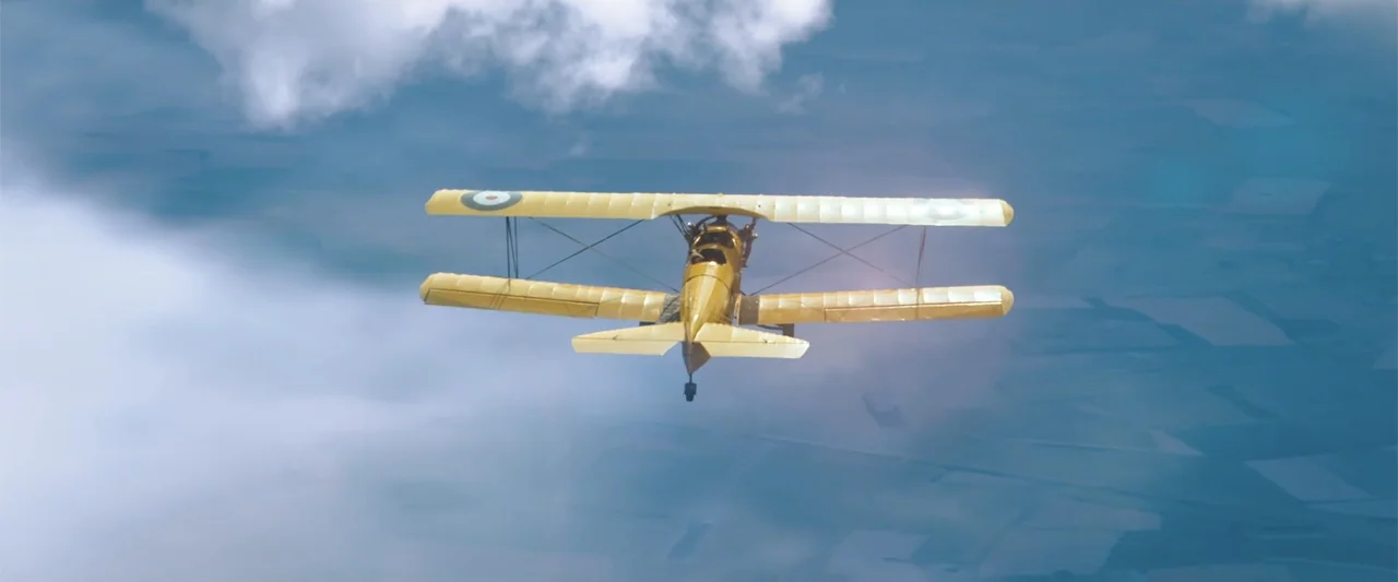 Hector and the Search for Happiness (2014) movie still: wide — A vintage biplane flies through the air above a distant landscape. The aircraft moves…