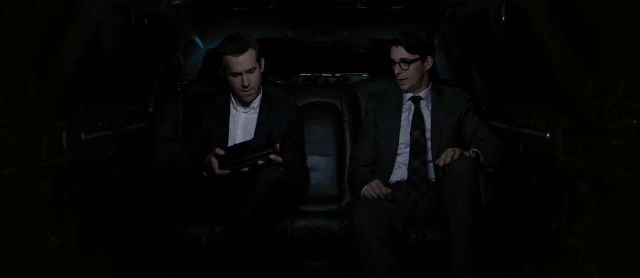 Self/less (2015) movie still: medium — The back seat of a dark luxury vehicle with black leather upholstery. Two men in formal business attire sit…