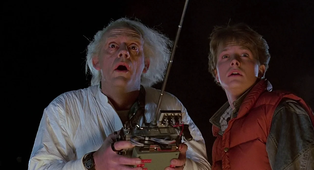 Back to the Future (1985) movie still: medium — A dark night setting with black void surrounding two subjects standing closely together. The…