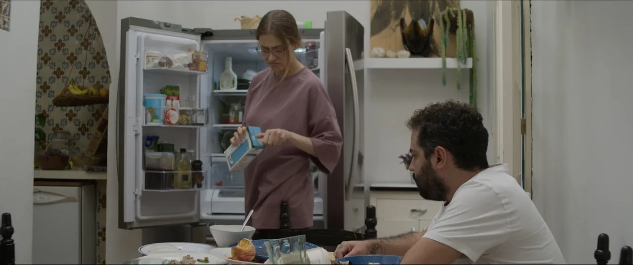 Can't Quit Mom (2022) movie still: medium — A residential kitchen featuring a stainless steel refrigerator and patterned tile wall sections. A woman…