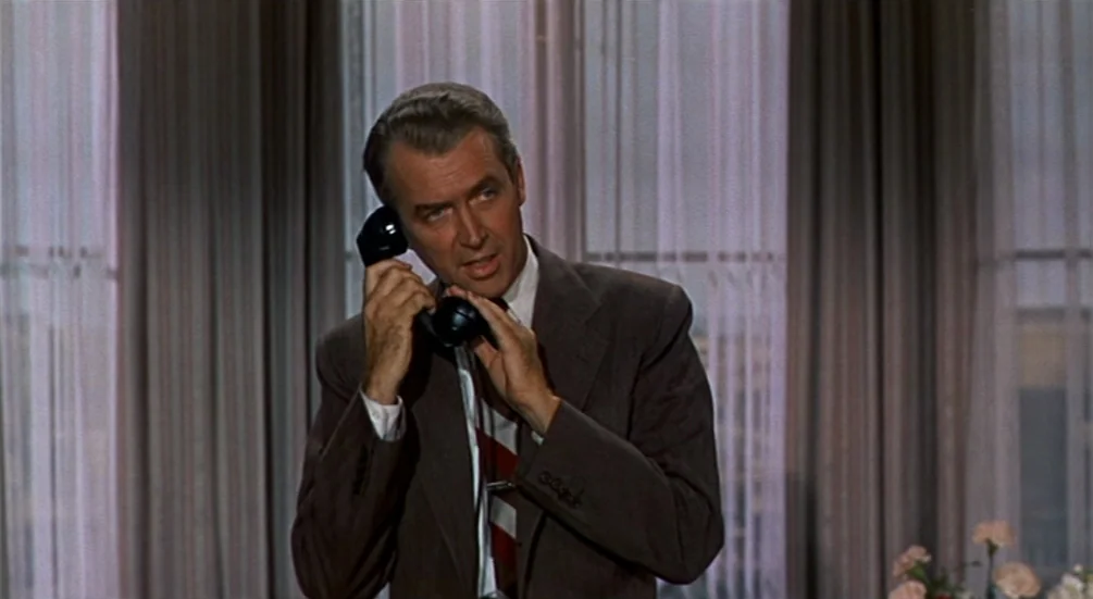 The Man Who Knew Too Much (1956) movie still: medium — An interior space with vertical translucent curtains hung over large windows in the back. A…