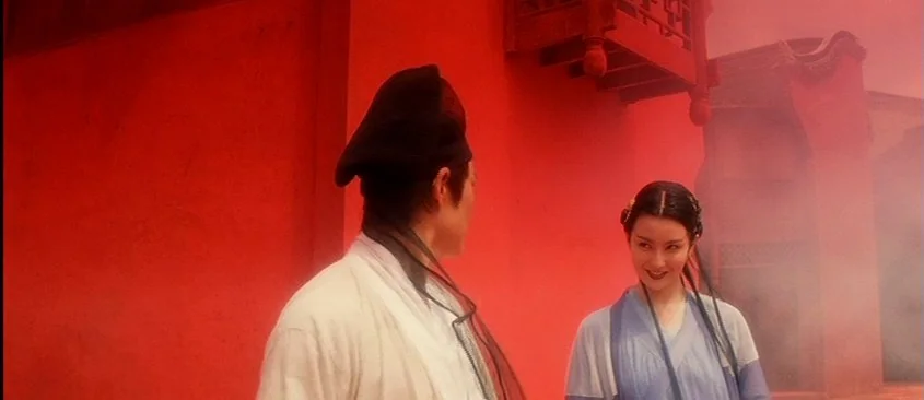 Green Snake (1993) movie still: medium — A courtyard defined by bright red walls and traditional wooden architecture. A man in historical robes and…