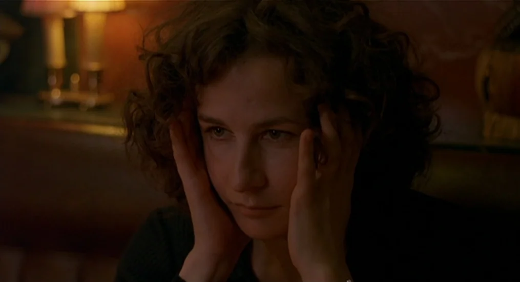 Vendredi Soir (2002) movie still: closeup — A dimly lit restaurant booth features warm lamps blurred in the background. A woman sits at the table…