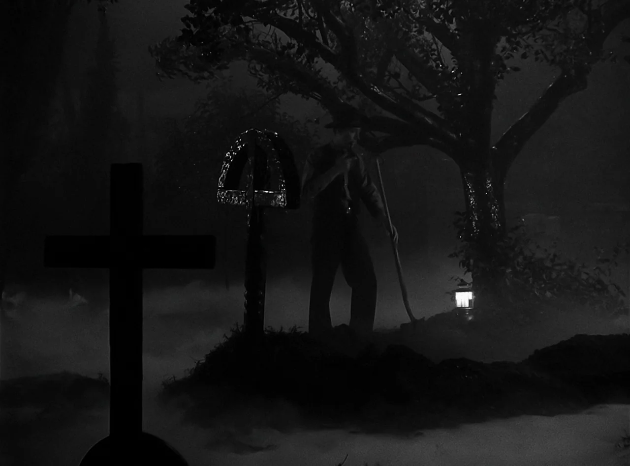The Wolf Man (1941) movie still: wide — A nighttime cemetery scene features thick ground fog surrounding several grave markers and trees. A man…