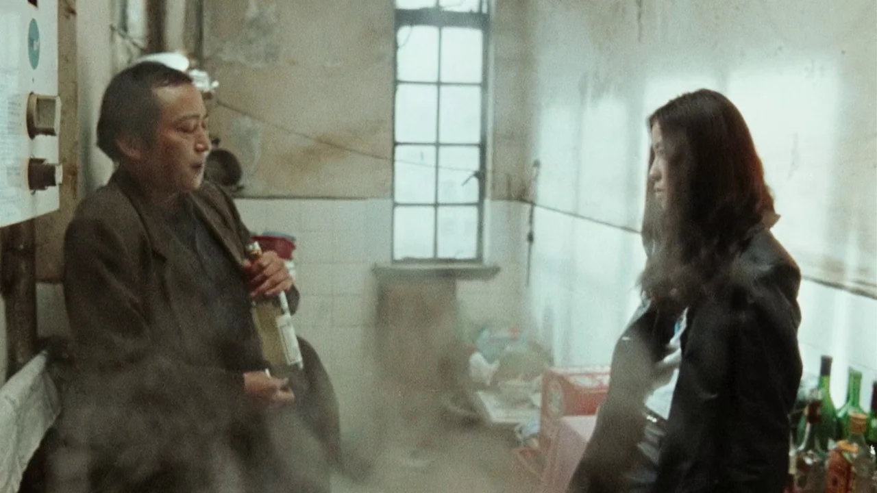 Suzhou River (2000) movie still: medium — A cramped, dimly lit room with peeling walls and white tiles is filled with steam. A man with a bottle…