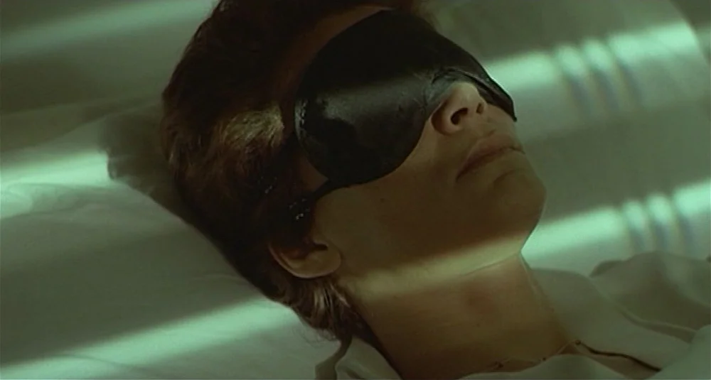 Footprints (Le Orme) (1975) movie still: closeup — A person lies on a pillow in an interior space during the daytime. Light filters through slatted…