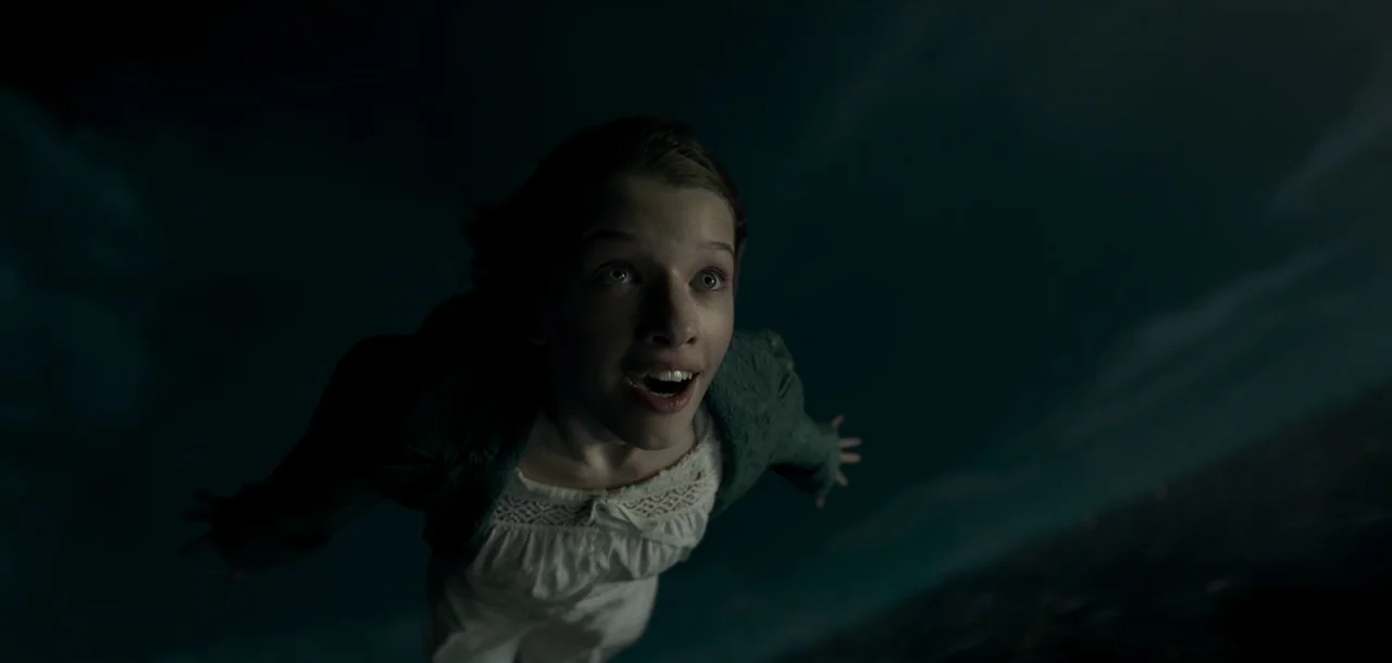 Peter Pan & Wendy (2023) movie still: medium — A young girl is positioned in a vast, dark, featureless space representing the night sky. She floats…