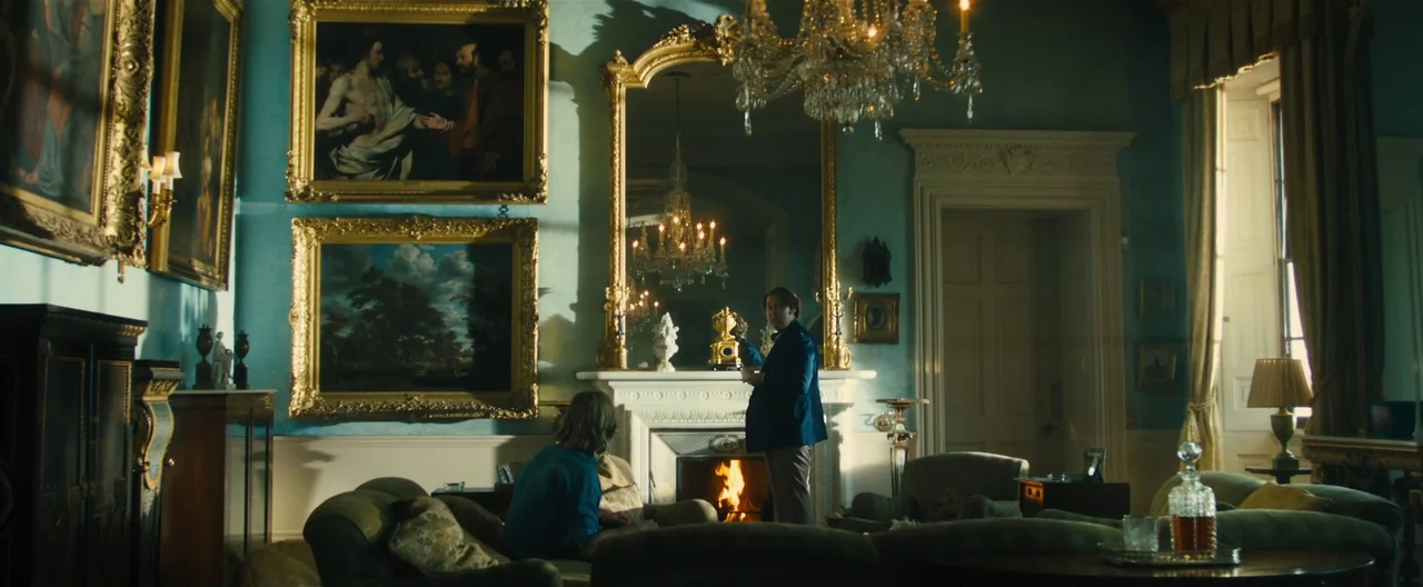 Rush (2013) movie still: wide — A grand, high-ceilinged room features light blue walls covered with ornate, gold-framed oil paintings. A man in a…