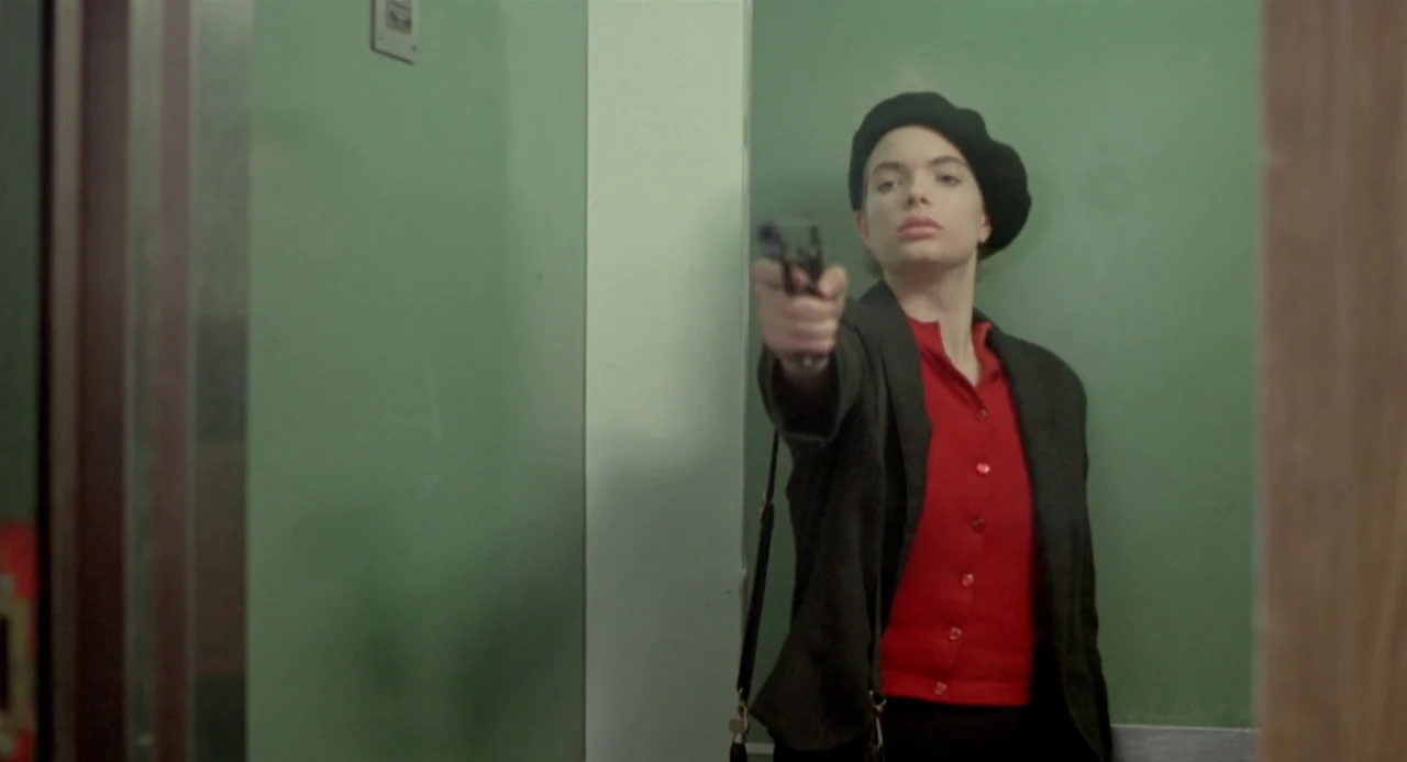 Ms. 45 (1981) movie still: medium — A compact elevator interior features plain green wall panels and a simple metal fixture. A woman wearing a black…