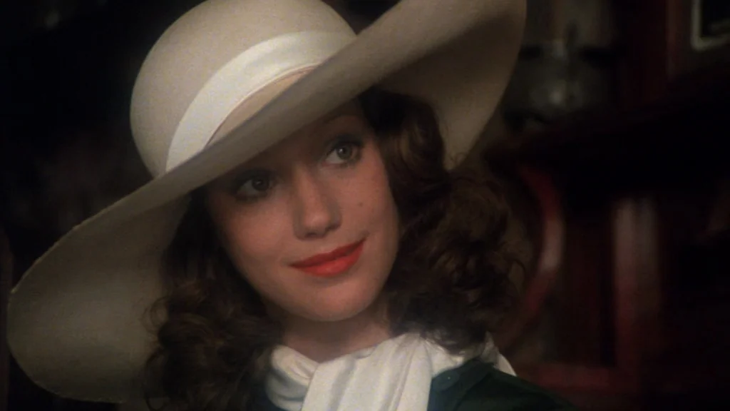 Cabaret (1972) movie still: closeup — An interior space with warm wood paneling visible in the soft background shadows. A young woman with a…