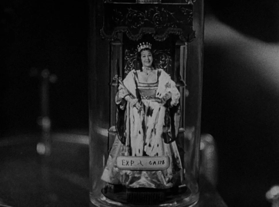 The Bride of Frankenstein (1935) movie still: closeup — A close-up view shows a drinking glass containing a printed image of a queen. The glass…