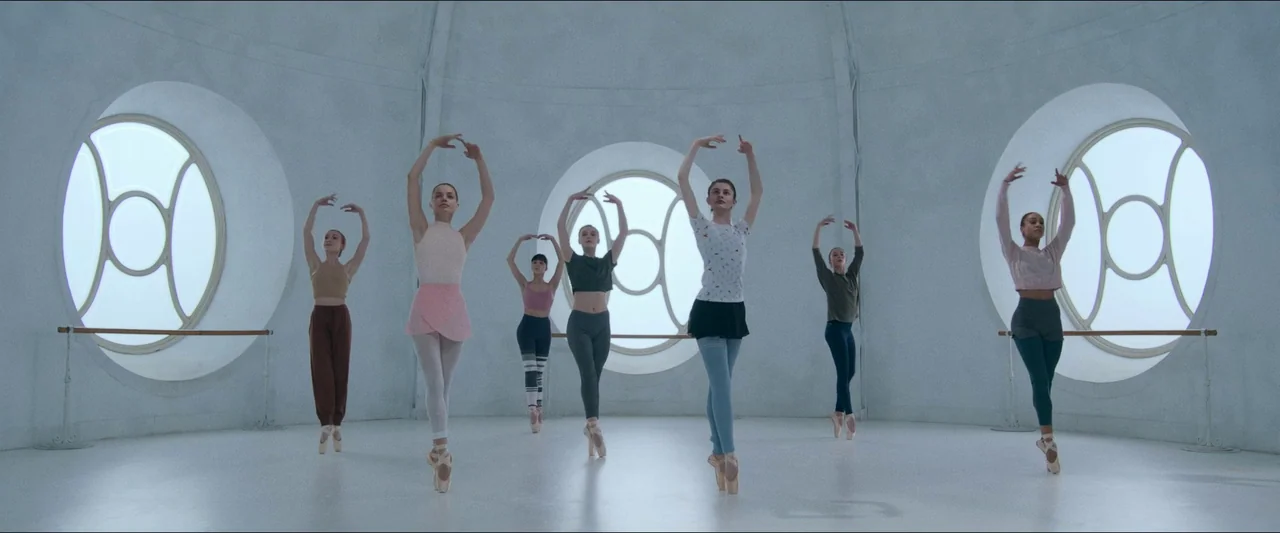 Birds of Paradise (2021) movie still: fullbody — A spacious room features white curved walls and three large circular windows. Six female dancers…