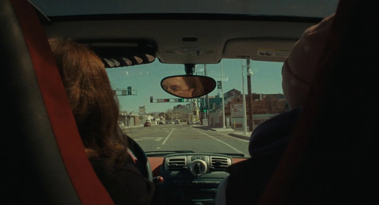 When You Finish Saving The World (2022) movie still: medium — The interior of a moving car shows the driver and passenger from behind. The rearview…