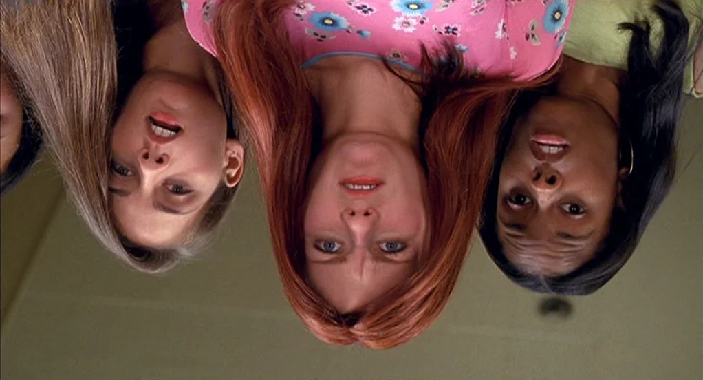 Spider-Man (2002) movie still: medium — Three teenage girls look down from above at the camera lens. The scene is brightly lit with a clear view of…