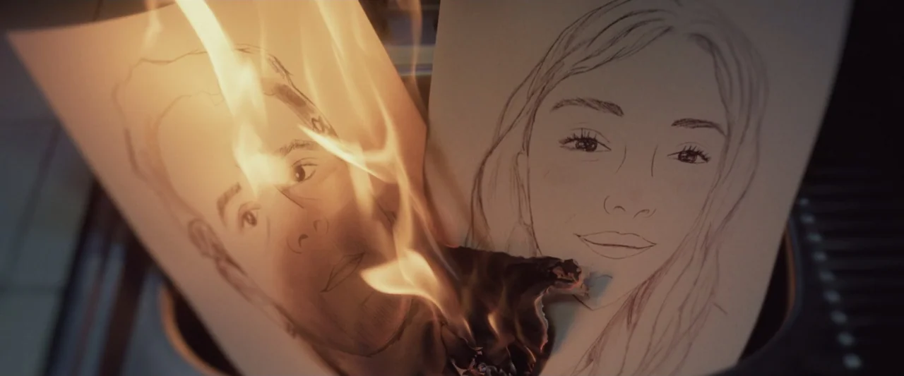 Sign Here (2017) movie still: closeup — Two pencil-sketched portraits on paper are being consumed by active flames within a container. The edges of…