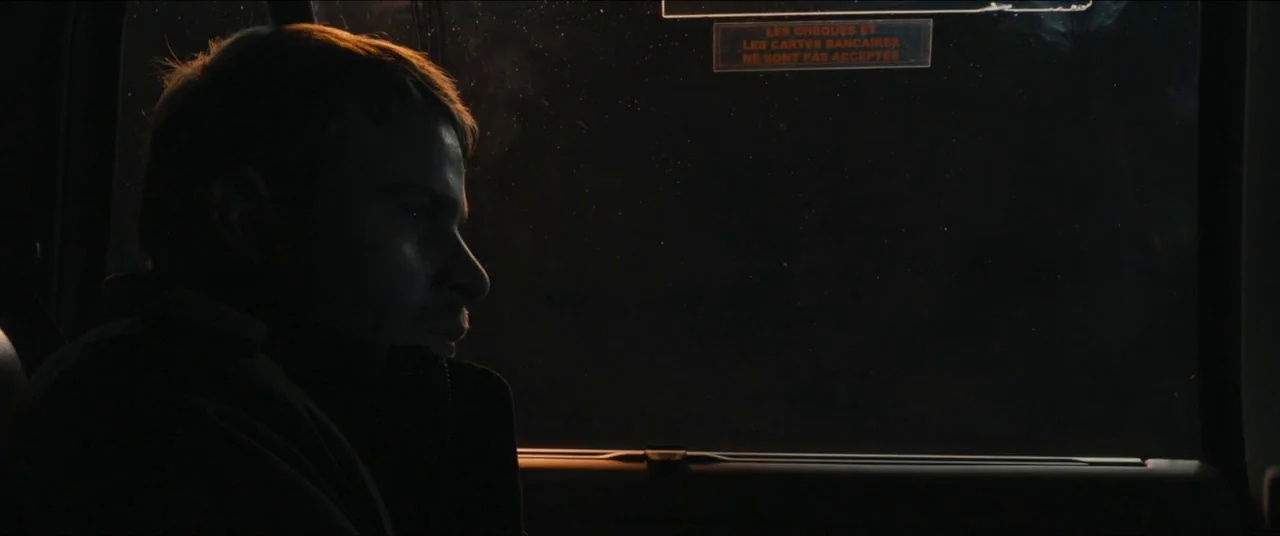 Simon Killer movie still: medium — A man sits inside the darkened interior of a vehicle at night. He stares through the window at the passing…